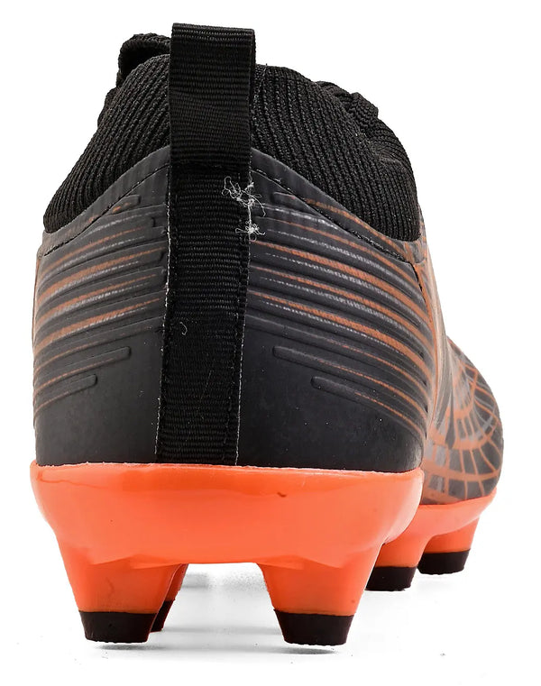 Chuteira de futebol preta com detalhes laranja e sola de cravo vista de trás, com puxador na cor preto, ideal para campo.