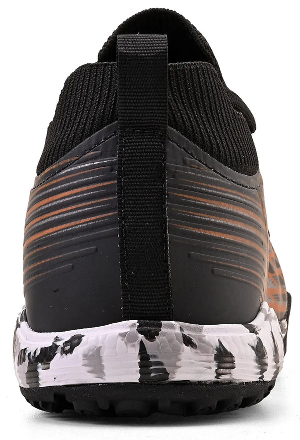 Imagem de chuteira preta com detalhes laranja, vista de trás, com solado brancos com manchas pretas, ideal para corrida ou treino.